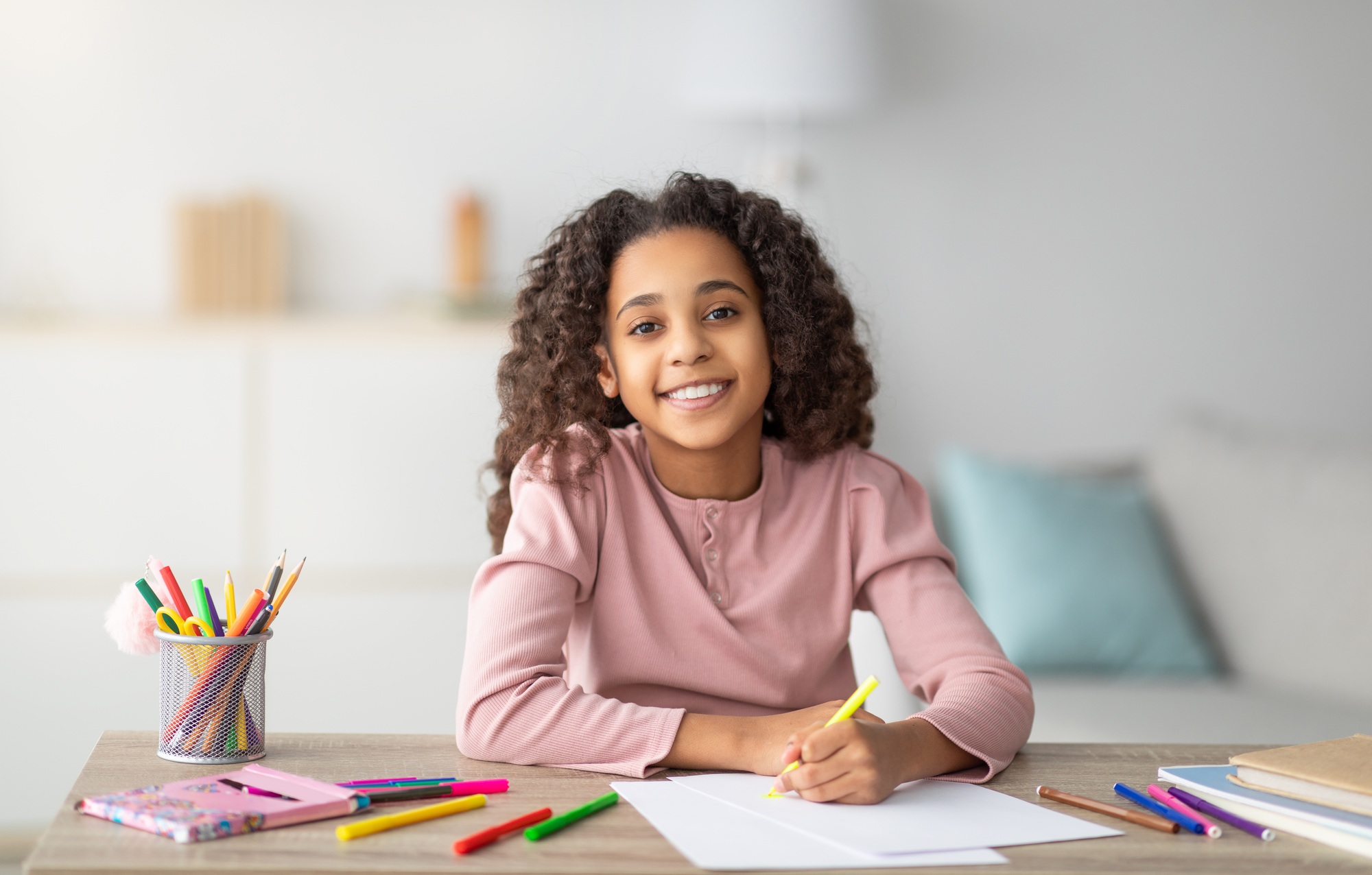 Happy black schoolgirl drawing picture at home